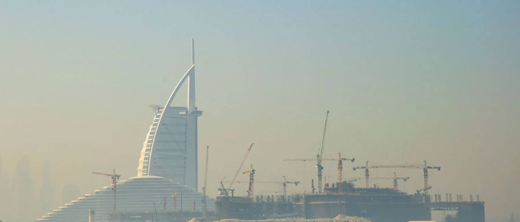 Cranes and towers under construction against the Dubai skyline